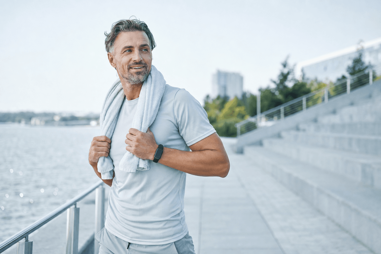An energized man in his 40s with a towel around his neck after an outdoor morning workout
